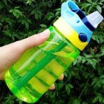 480 ml non-leak water bottle with lid and straw in green, yellow and blue in front of a tree