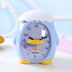 Bird-shaped alarm clock for children on a white table and blue background