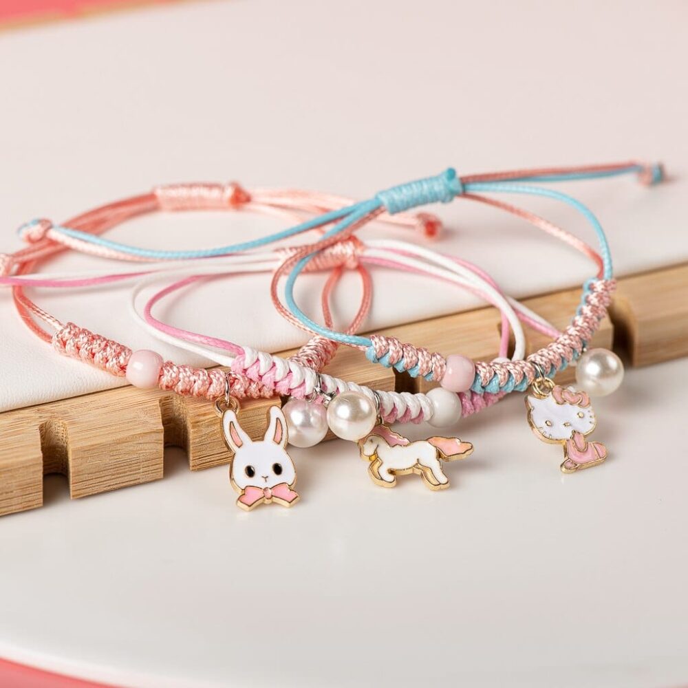 Bracelet with pearl pendant and pink and blue animal on white and wood background
