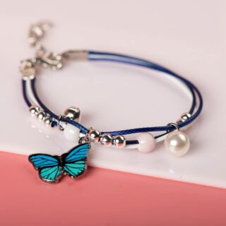 Bracelet with blue butterfly pendant with white pearls on white and pink background