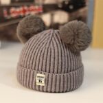 Knitted hat with double brown pompon on a table