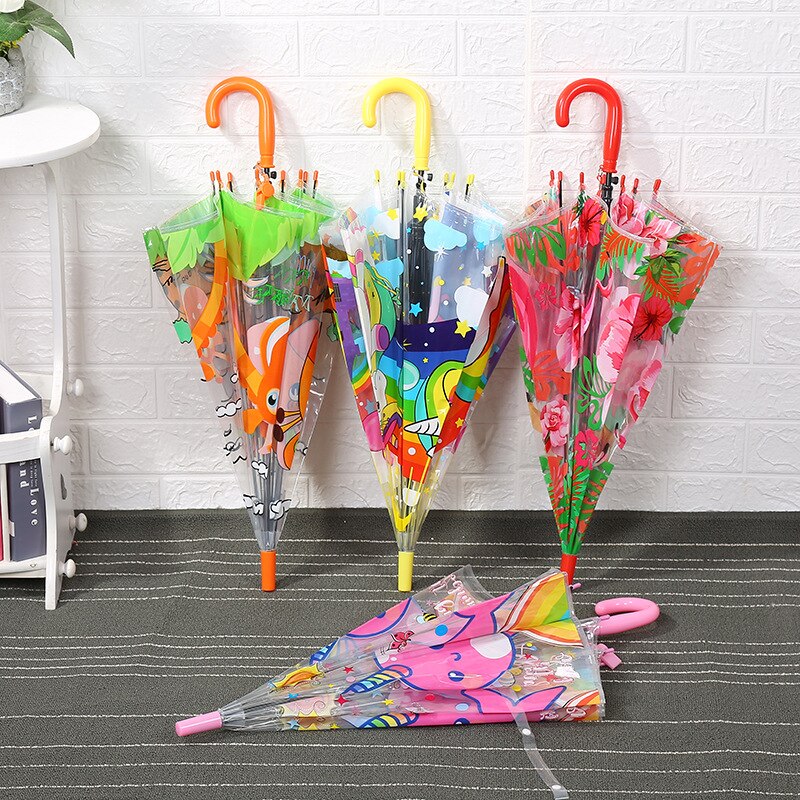 Transparent umbrella with cartoon motif for colorful children against a white wall on a gray floor
