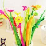 20 pieces of colored flower-shaped ballpoint pen in a white pot on a tabletop