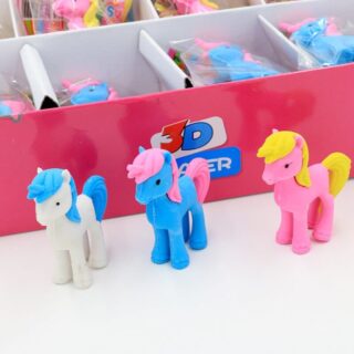 3 pieces of white, blue and pink unicorn-shaped erasers next to a pink box on a white table
