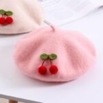 Plain cherry beret for a pink girl on a white table