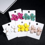 Flower-shaped earrings for girls in white, yellow, pink and green with label on black background