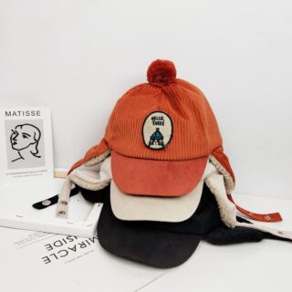 Orange, beige and black children's winter cap on a white background on a table