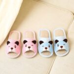 Pink and blue striped teddy bear slipper on a beige carpet next to a bed