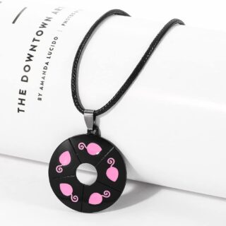 Children's necklace with black and pink mouse pendant with black thread on white ul book