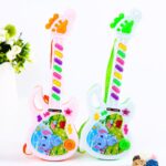 Electric guitar with cartoon motif for colorful children, next to a green plant and in front of a white wall