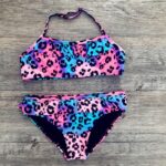 2-piece leopard print swimsuit for girls in pink, purple and blue on grey wood