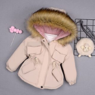Solid color parka with fur hood in beige on a grey wall with black iron basket