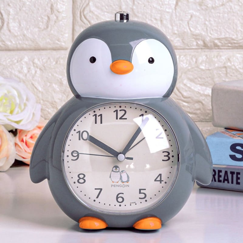 Multifunction alarm clock in the shape of a grey, white and orange penguin on a white shelf
