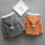 Children's grey and brown velvet hooded jacket with pompon on grey background with molding