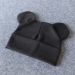 Cotton bonnet with little ears for baby in black on grey background