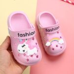 Fun pink children's unicorn slippers on one hand with colorful pattern