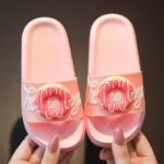 colorful summer flip-flops for girls in pink with donuts on a woman's hands