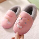 Pink and grey baby unicorn slippers on a white carpet