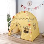 Cute little children's yellow tepee in a room in front of a window
