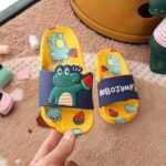 Children's yellow and blue crocodile flip-flops with hard crocodile motifs in the hand of a person