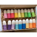Colorful wooden peg dolls for children in a cardboard box