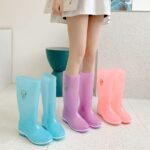 Blue, pink and orange transparent rubber rain boots in a girl's feet