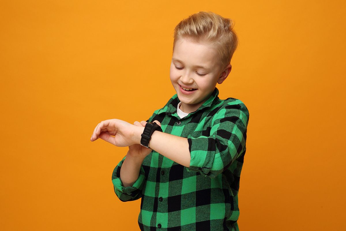 A young blond boy wearing a green checkered shirt and a child's watch