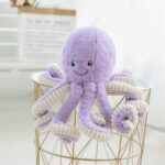 Super cute octopus plush in purple on a gold and white bedside table