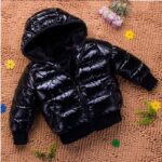 Children's padded cotton down jacket in black on a brown carpet with flowers