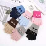 Cute knitted cat gloves for kids with ears on white books