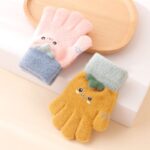 Warm winter cashmere gloves for orange and pink children on a white table