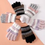 Soft knitted winter gloves for children colored with winter motis on a coral and white background