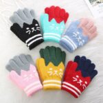 Cute cat cartoon winter gloves for kids with cat motif on front on a white carpet