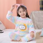 Fleece pajamas with colorful moon motif for children with cloud motif in front in a living room on a white carpet