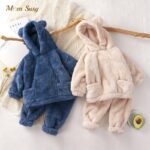 Hooded fleece pajamas with bear ears for kids in beige and blue on a white carpet