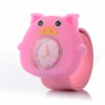 A children's watch in the shape of a cute pink pig. At its center is a glass dial with colored hands and numbers.