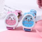 watch for girl, two colors of the same model are presented together, one pink and the other blue, they are on a pink support, the dial represents the head of a teddy bear