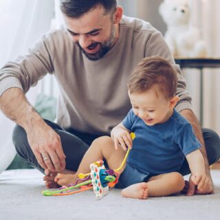 Montessori silicone teething game for babies with background, a dad with his baby